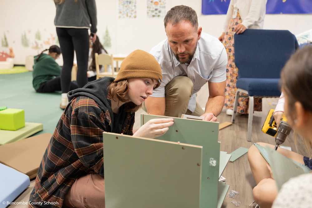 Student and teacher building a children's play kitchen for the indoor playroom at Collins Early Learning Center. 