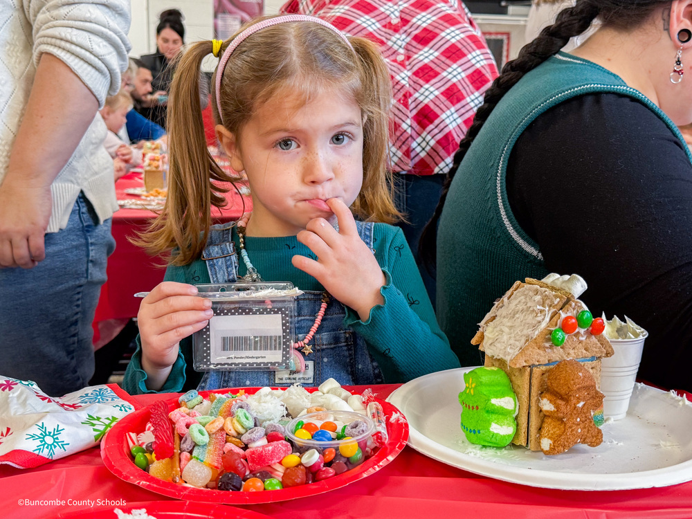 Little girl decorating a gingerbread house