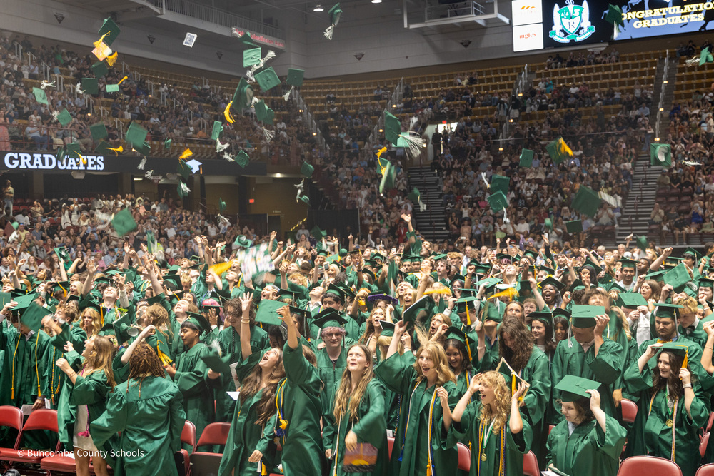 Graduates toss their caps up into the air.
