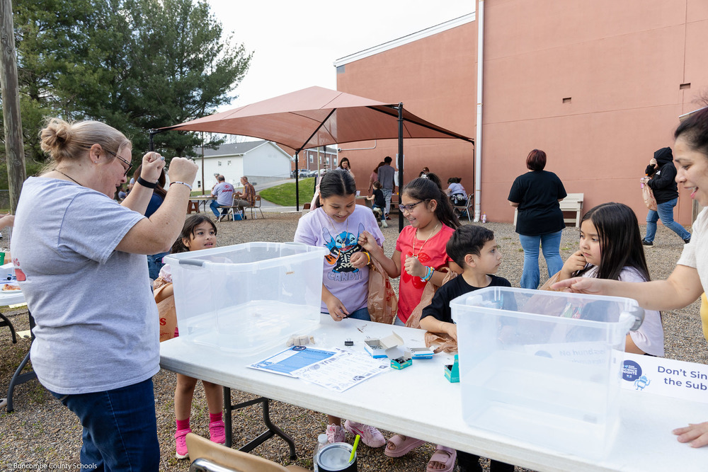 A group of kids react to a science demonstration involving buoyancy.