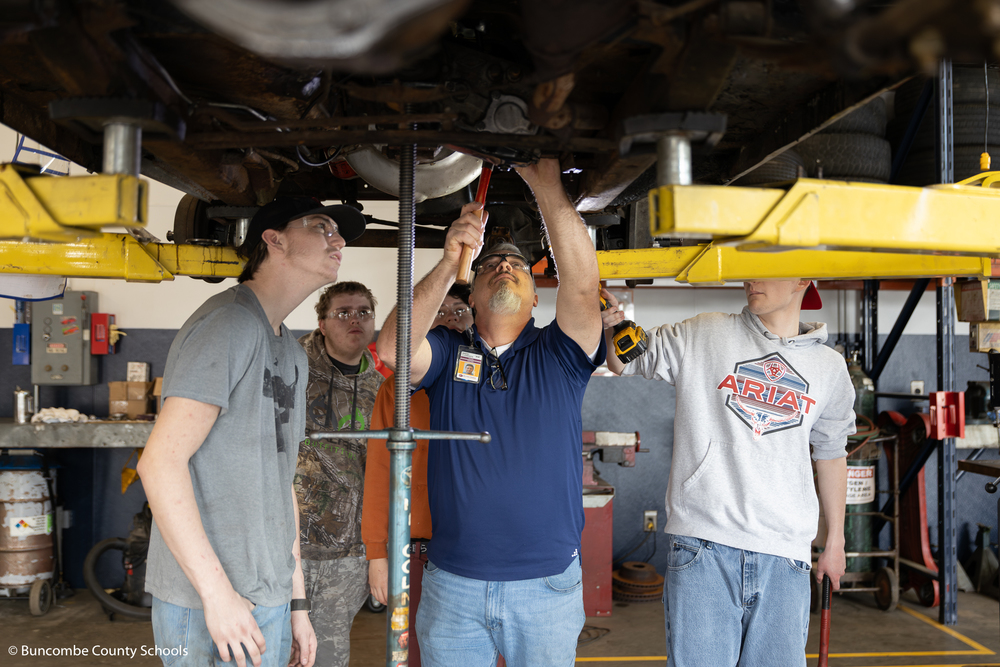 Mr.  Clements showing the students underneath a vehicle. 