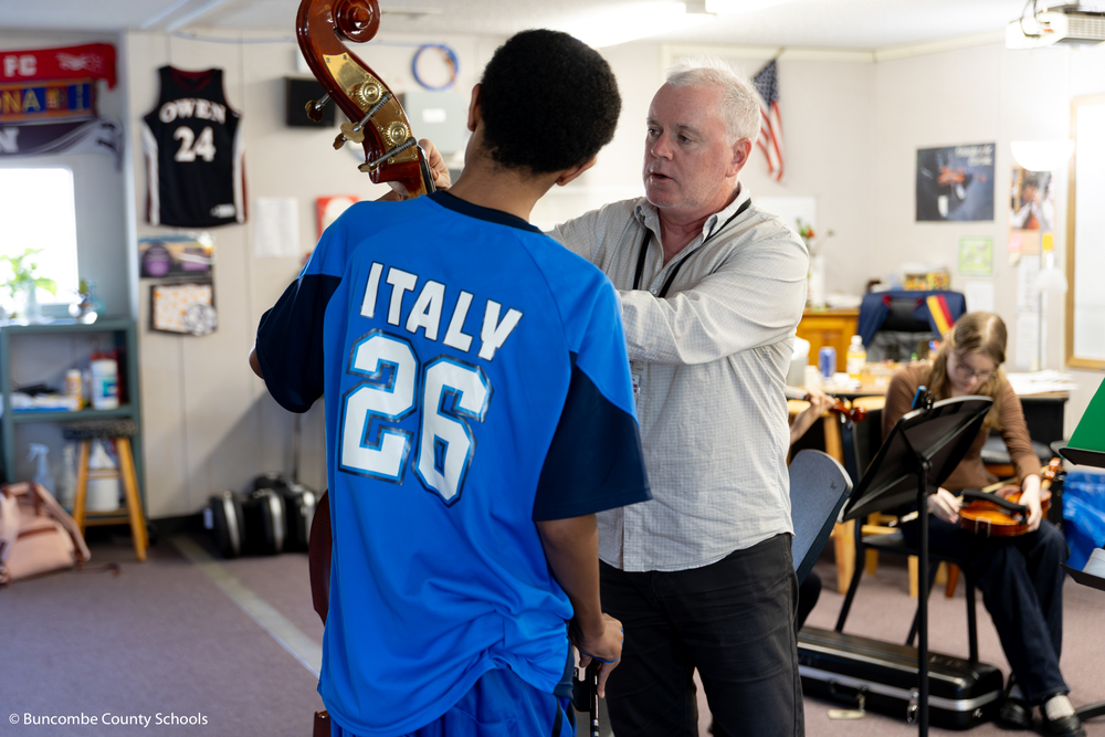 Mr. Kinne helping a student play the bass. 