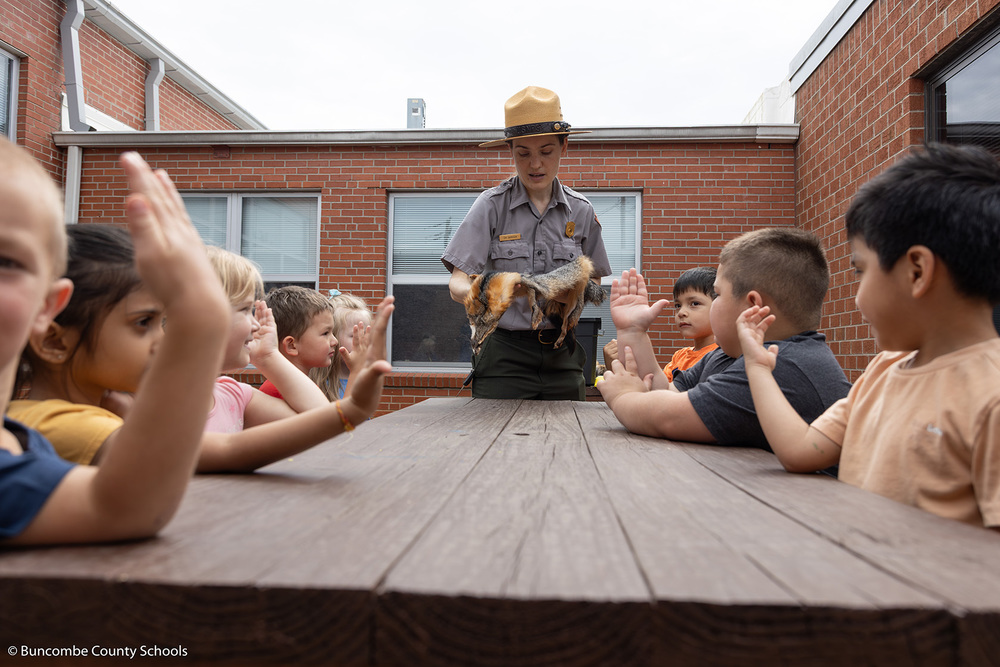 Park ranger showing kids a fox fur. 