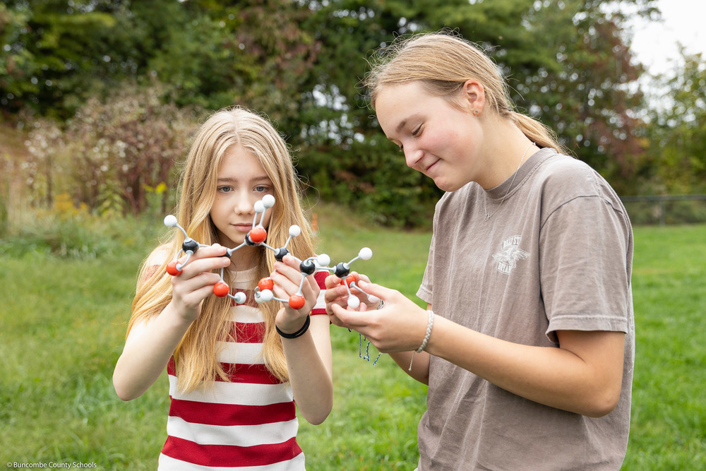 Two students hold a model of a molecule.