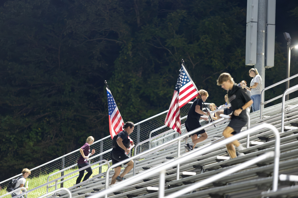 Community members carrying the American flag up the stadium stairs. 