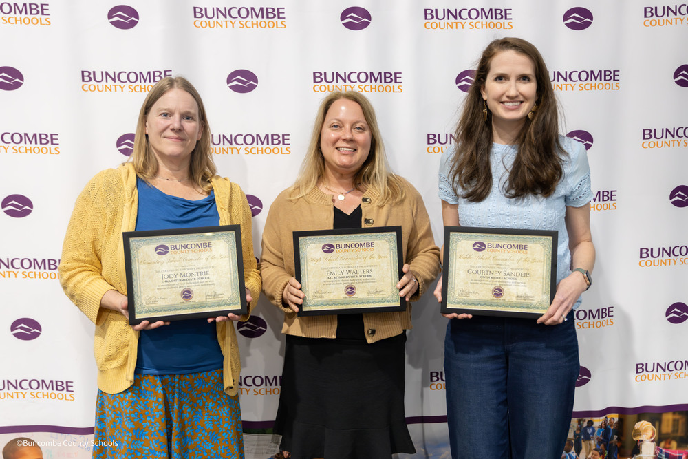 Ms. Montrie, Ms. Walters, and Ms. Sanders pose in front of the BCS banner holding their certificates