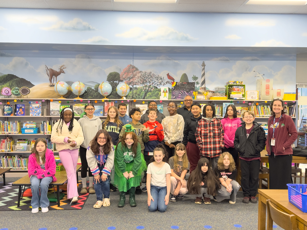 Group photo of the fifth grade class standing with Rev. Charles Martin. in the Media Center. 