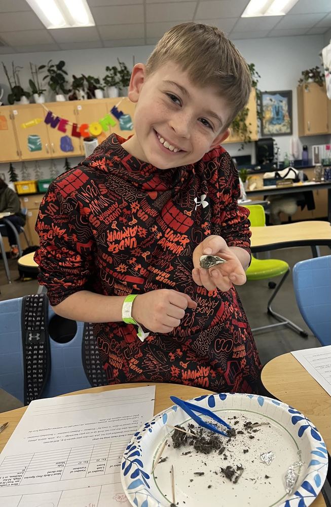Student holding an owl pellet and smiling for the camera. 