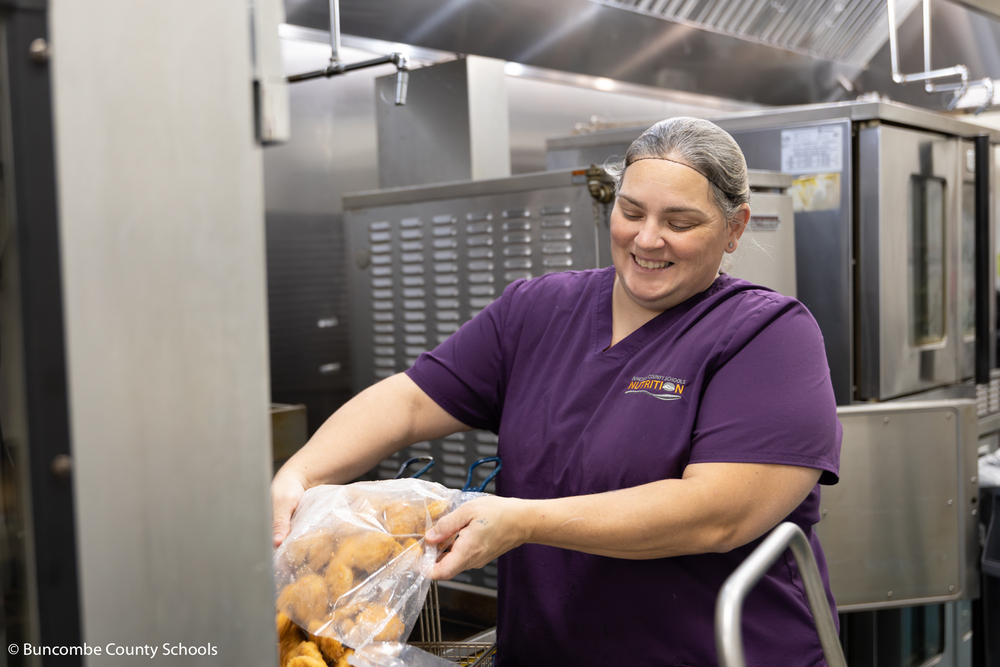 Serena putting chicken nuggets into the fryer. 