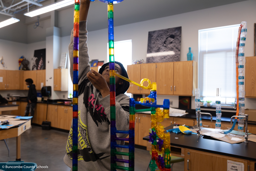 Student adding pieces to their miniature rollercoaster to make it taller. 