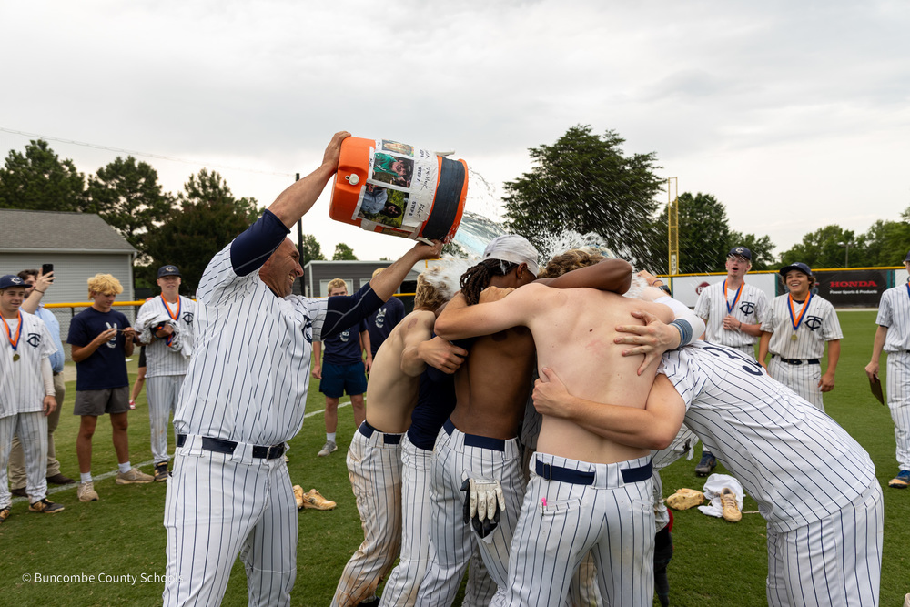 Coach Filipek dumps a cooler of water over his players huddled together on the baseball field.