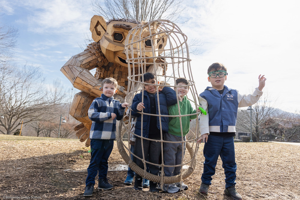 Four students pose with one of the troll designs.