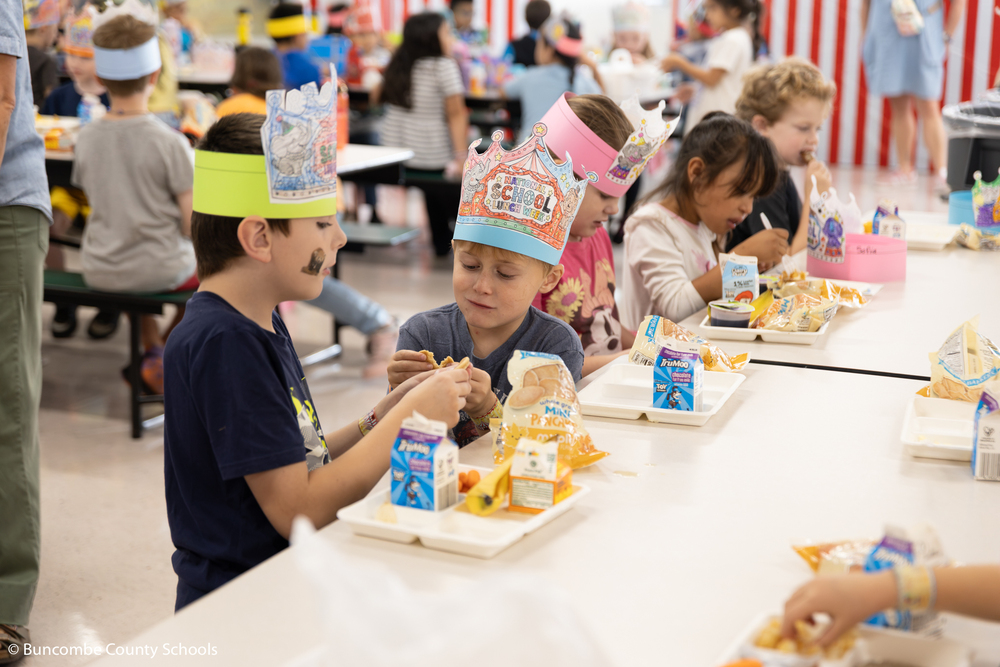 Two boys talking an enjoying their school lunch. 