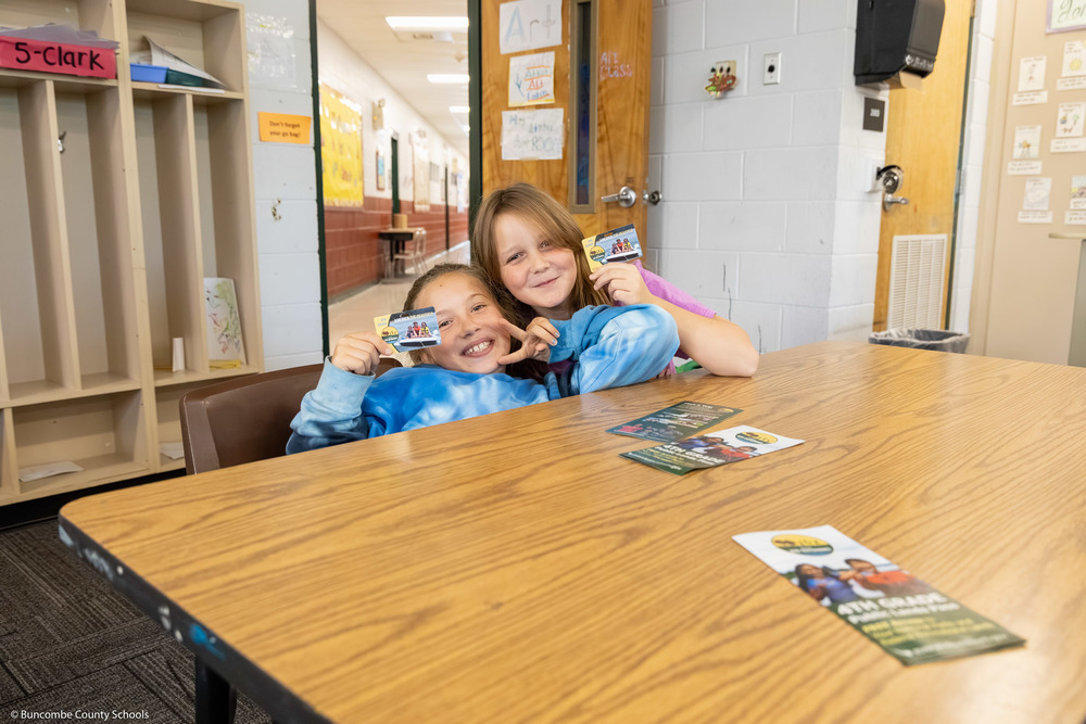 Two students hold up their passes.
