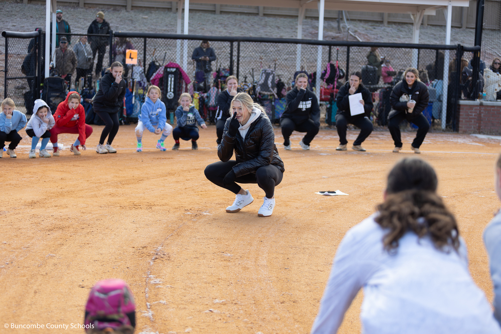 Karlyn Pickens in the center of the circle playing Simon says with campers. She has her finger on her nose.