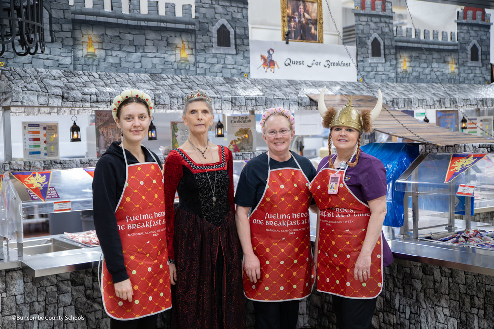 four child nutrition workers in  various medieval costumes in front of castle themed serving line