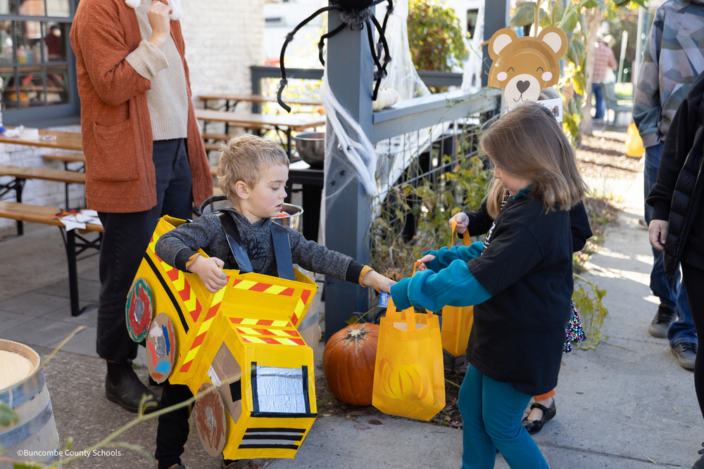 Child handing out candy to a WPS student on the fall walk
