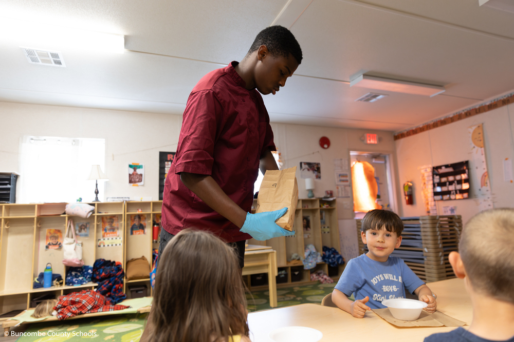 Owen student serving snack to PreK students. 