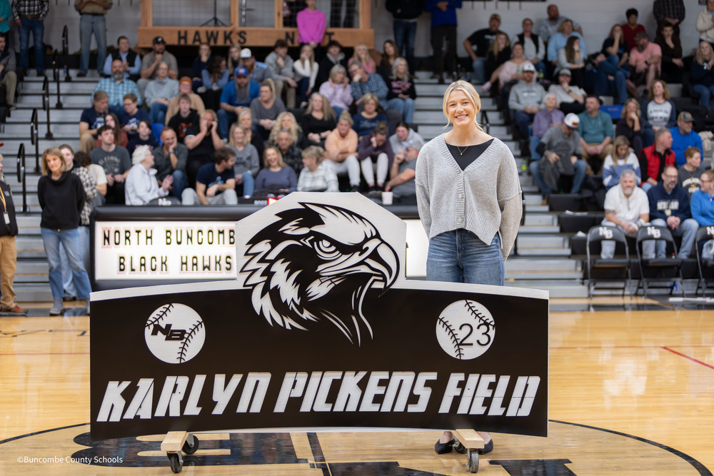 Karlyn Pickens stands with new sign for Karlyn Pickens Field