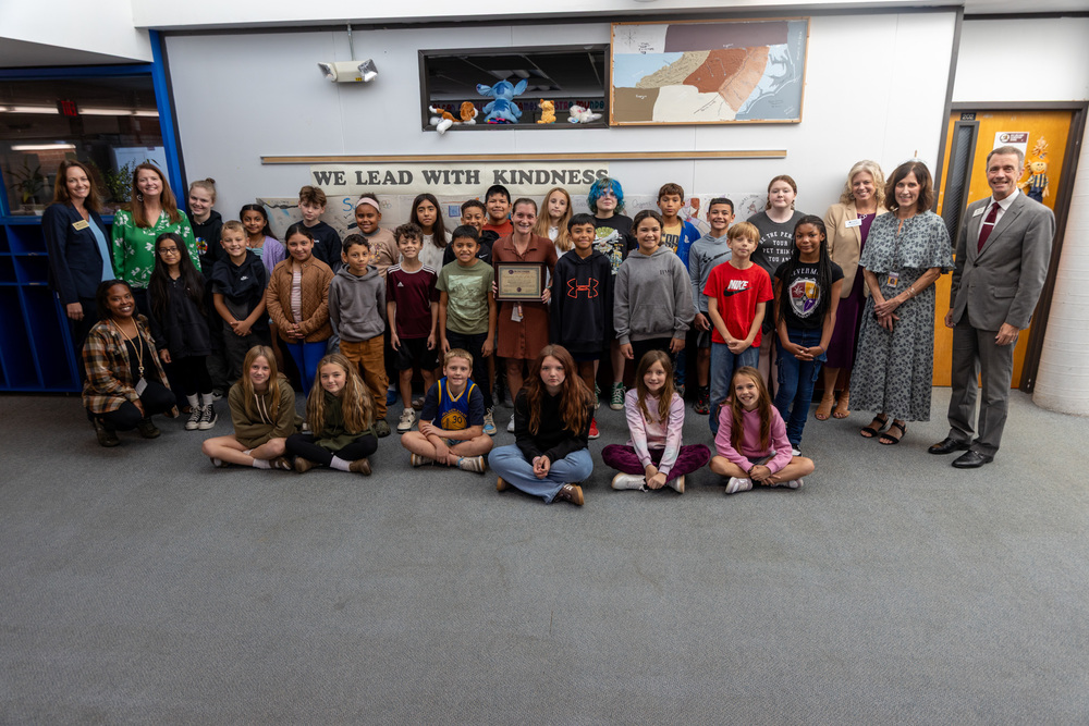 Ms. Van Etten, holding her plaque, poses for a photo with all of her students, the principal, and BCS superintendents in the hallway of W.D. Williams Elemenatary