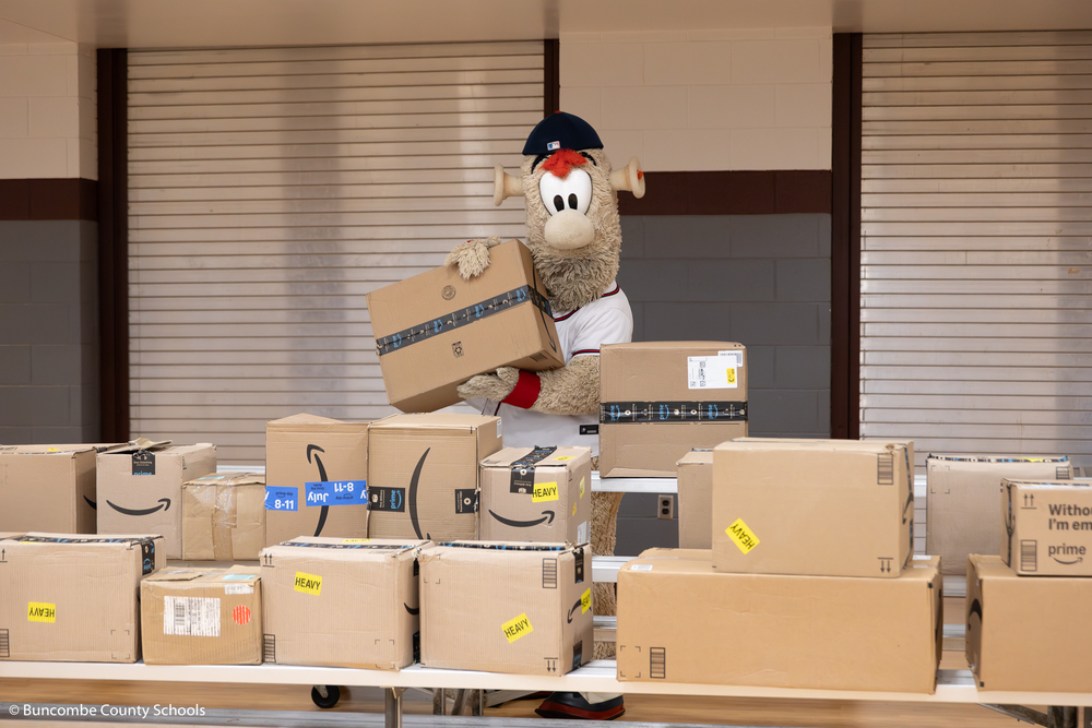 Blooper, the Atlanta Braves mascot, putting boxes of school supplies down.