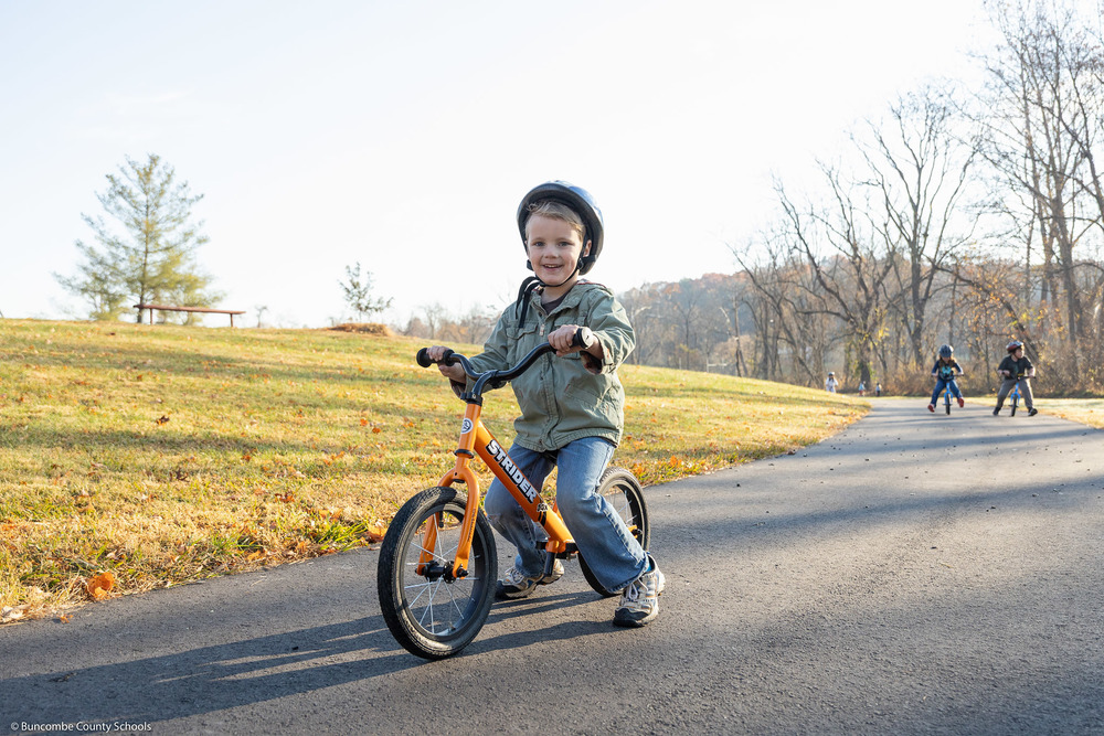 A student smiles while riding a bike.