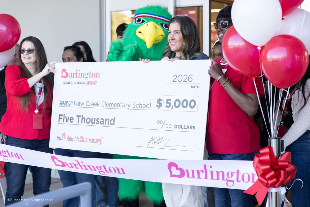 A picture of Burlington team members holding up a check. The Haw Creek Hawk mascot is in the background