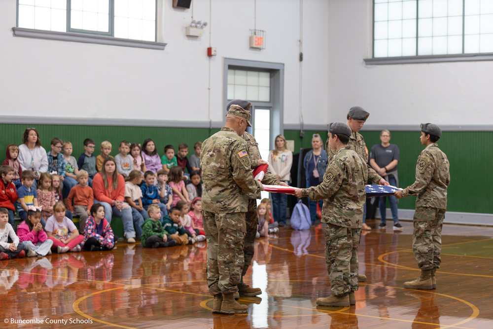 Erwin High JROTC folding the American flag during the Veterans Day program inside the gym at Barnardsville Elementary.