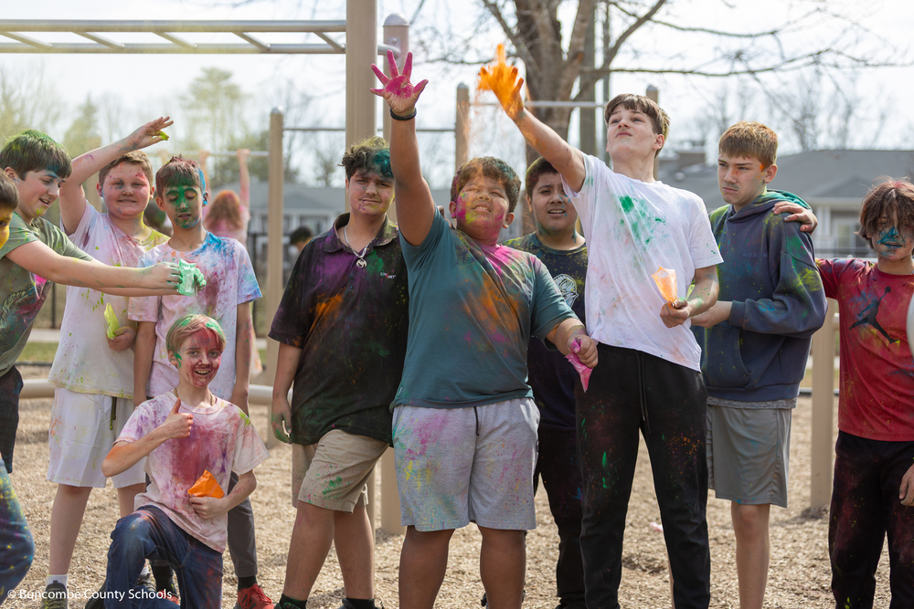 Group of students throwing a non-toxic colored powder in the air as part of the Holi celebration. 