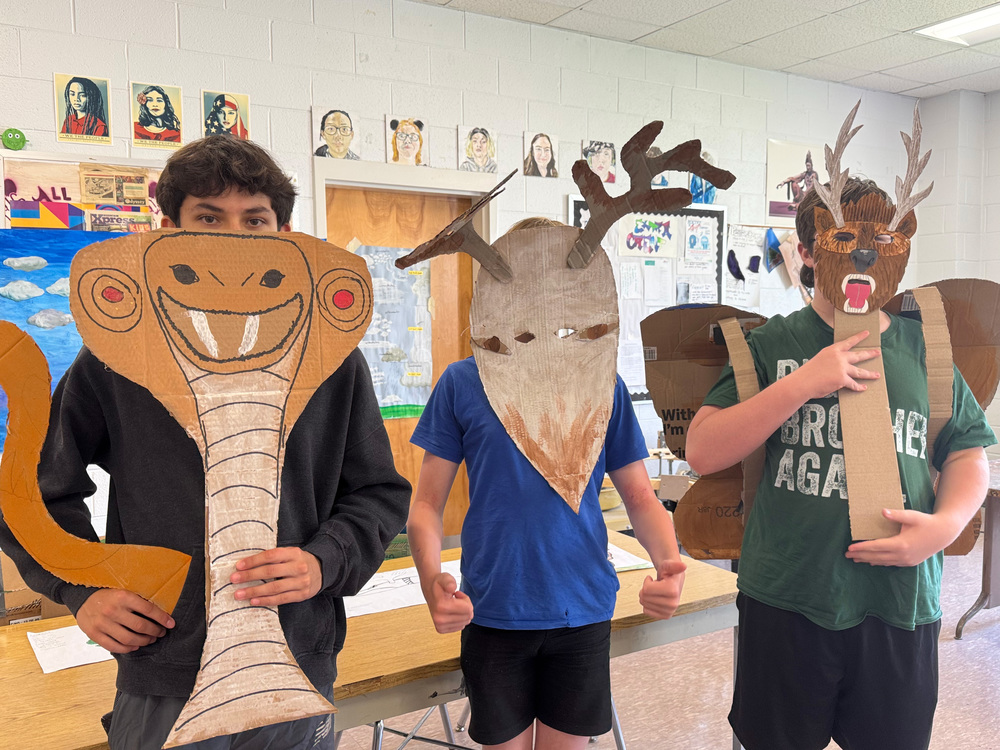 Students holding up masks they created in art. 