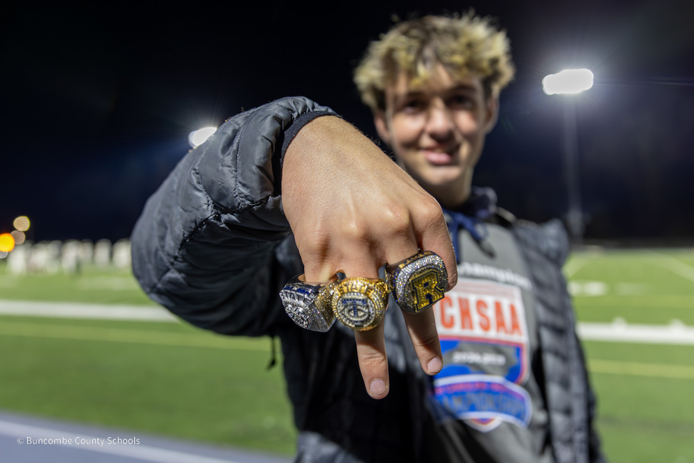 A closeup of a TC Roberson baseball  player's three championship rings on his fingers