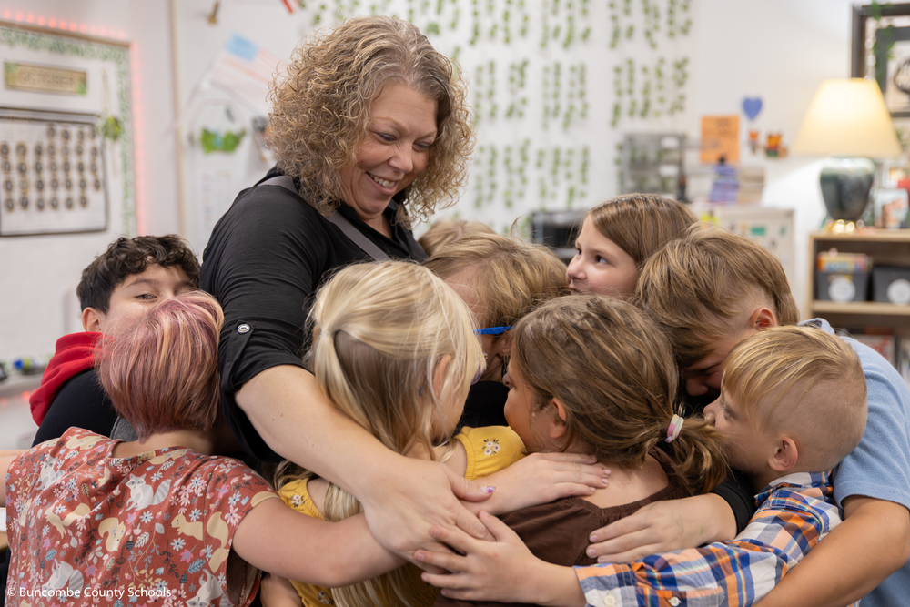 Principal Kelly Owen getting a group hug from a classroom of third graders. 