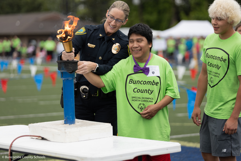 Asheville Police officer and Progressive Education student lighting the torch. 