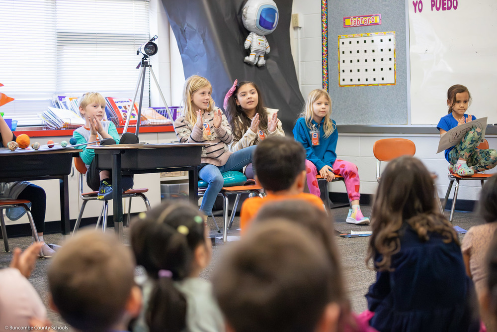Students clap as presenters talk about their planets.