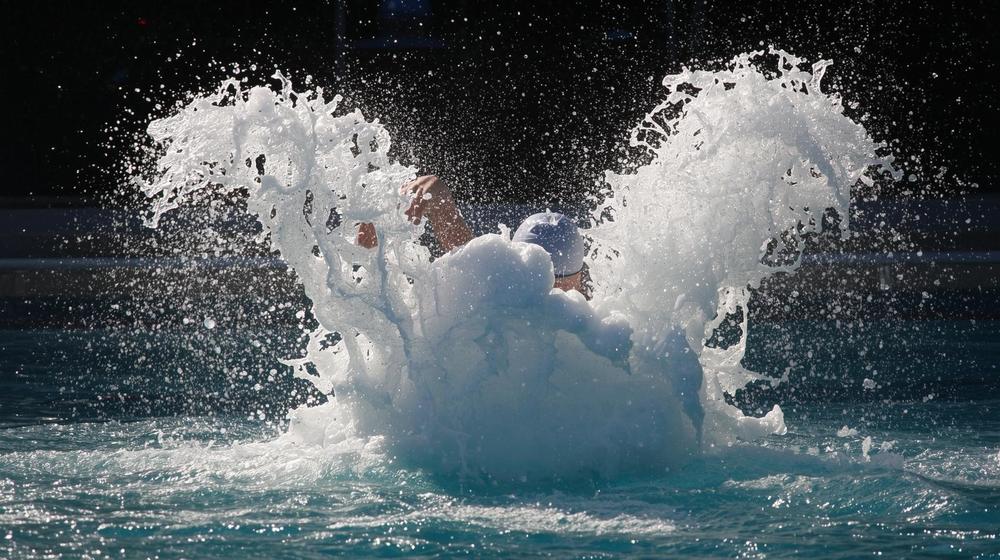 A diver makes a big splash jumping into a pool