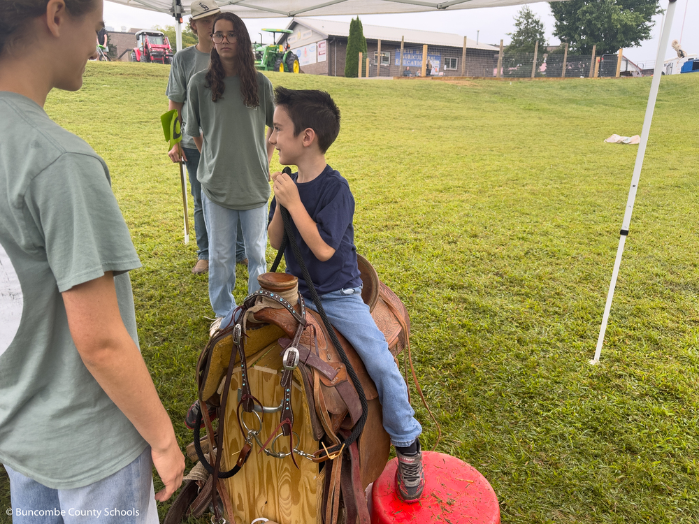 Second grader sitting on a horse saddle. 