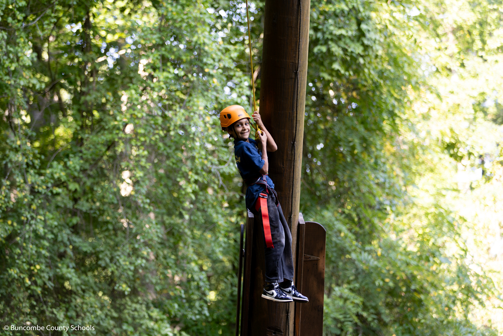 Student coming down from the ropes course. 
