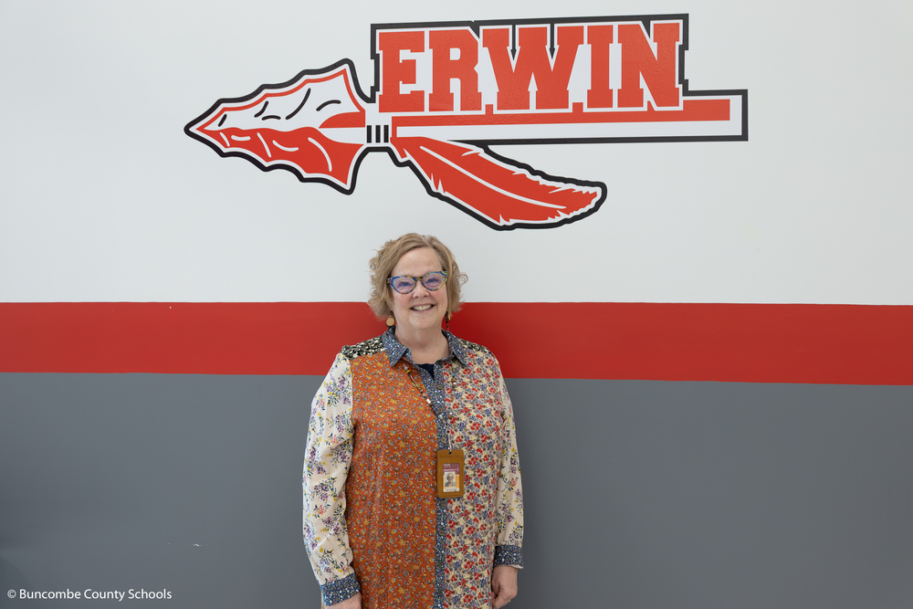 This is a photo of Shelly Roeder in front of the Erwin logo inside the school.
