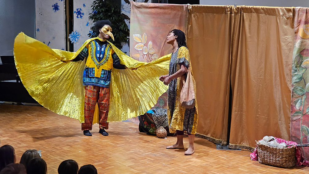 Actors from the Bright Stars Theater dressed up in vibrant colorful costumes. One Actor is a golden bird. 