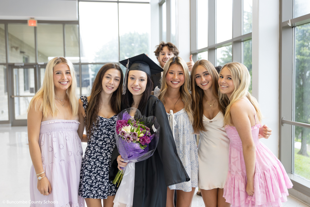 Summer graduate posing with friends for a photo.