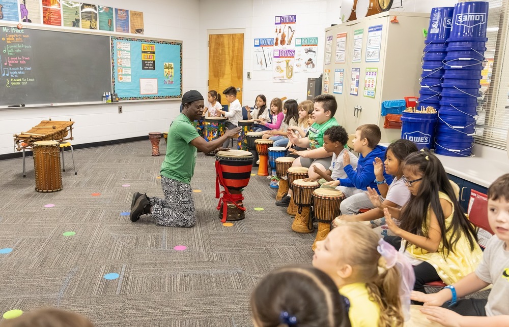 Adam Dembele leads a class through a hand drum routine in Preston Prince's music class.