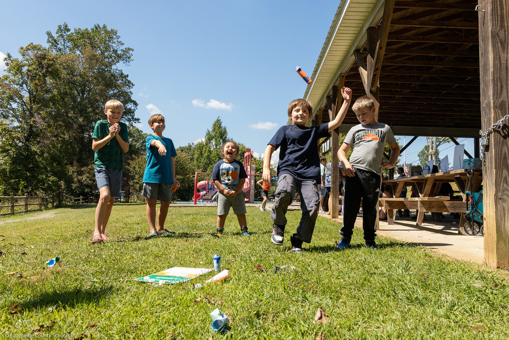 Five children react to a water bottle rocket.