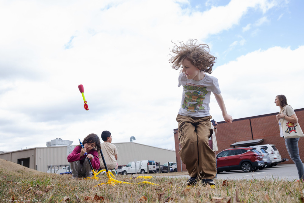 A student stomps on a rocket launcher as the rocket heads skyward.