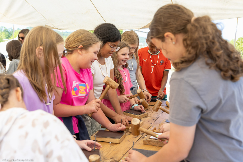 Students make journals with wooden mallets, nails, and leather.