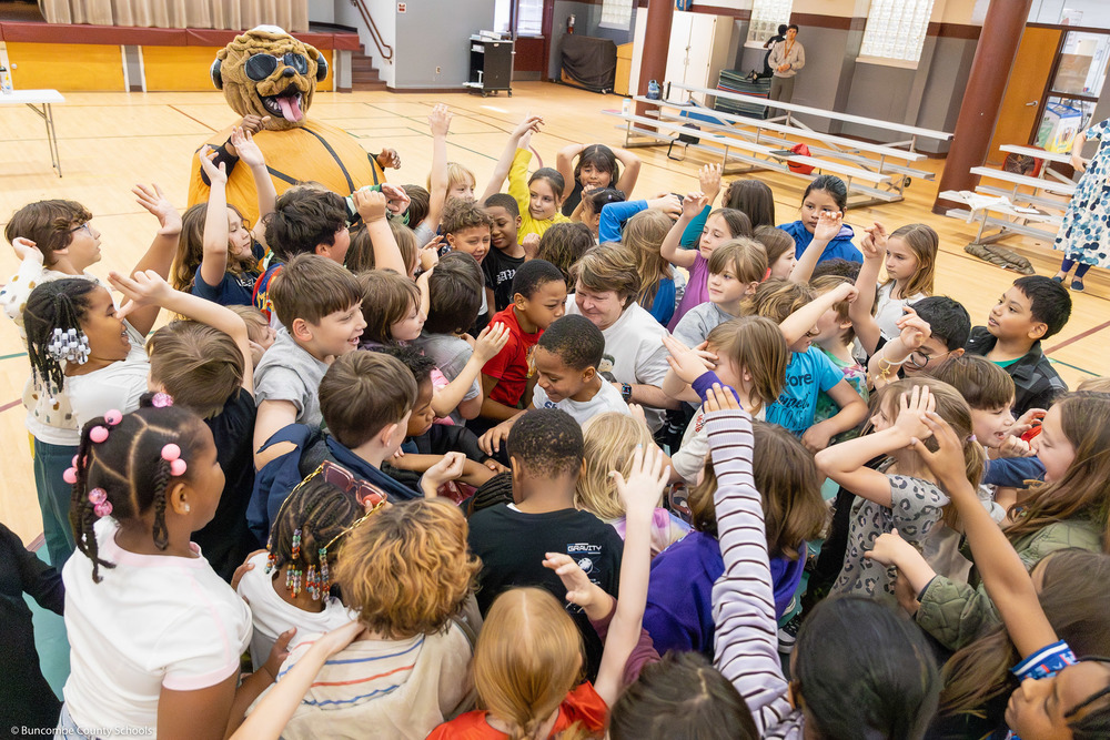 Susie Gardner stands in the center of a huddle of second graders.