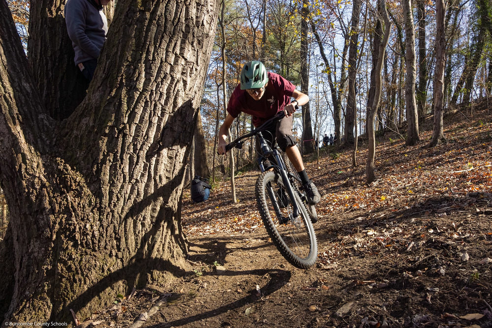 A student rides one of the mountain bikes down a trail.