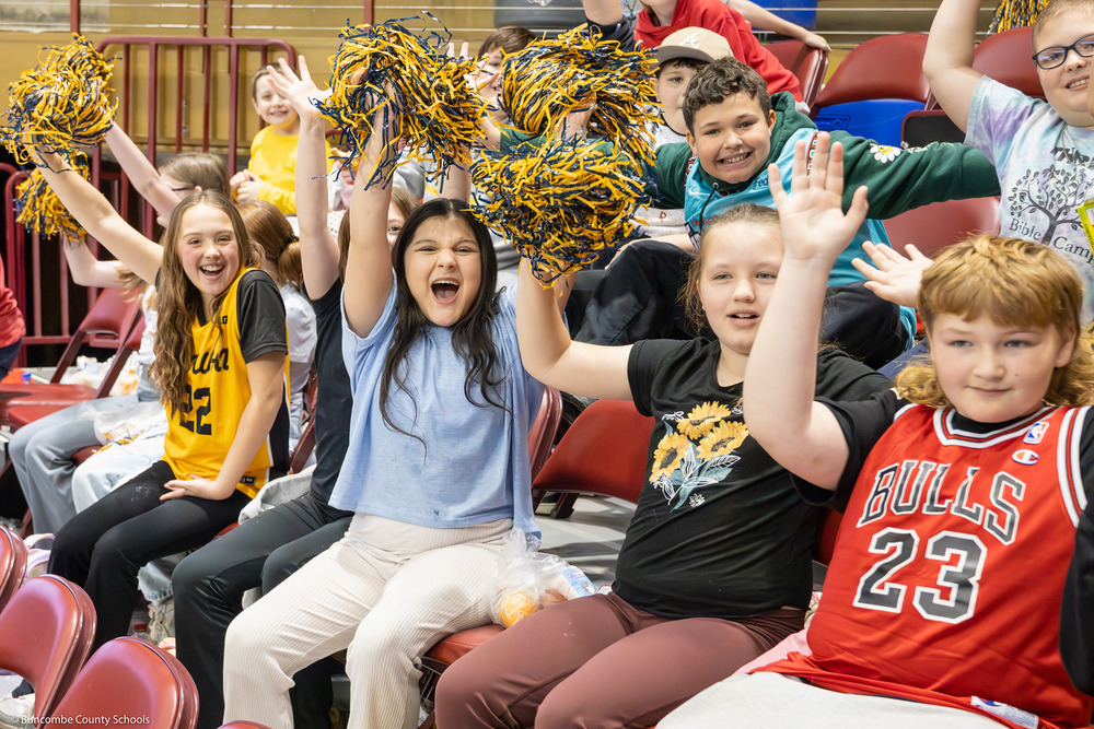 Students holding pom poms cheer while sitting in the stands at the 2025 SoCon Tournament