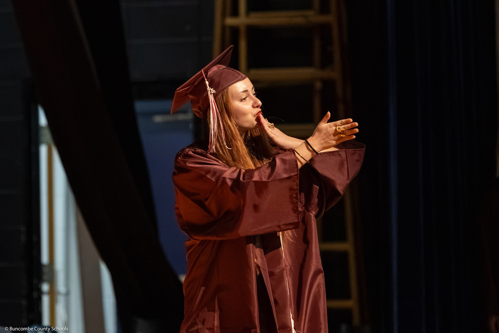 A graduate blows a kiss to her family.