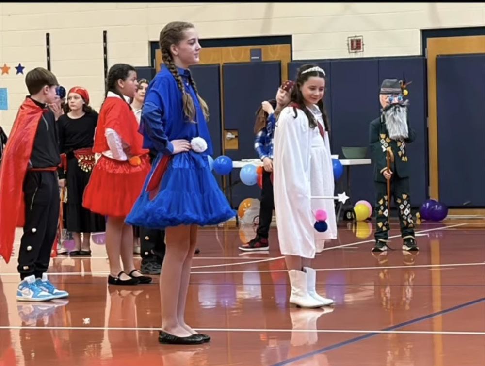 Students dressed in blue, red, and white performing chilean dance. 