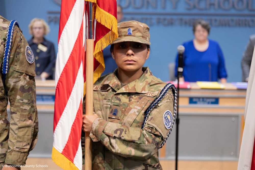 Enka JROTC cadet holds the American flag at a Board of Education meeting